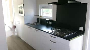 Een moderne keuken met witte kasten, een zwart aanrecht en een ingebouwde magnetron.