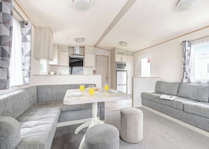 Un intérieur de camping-car moderne comprenant un coin repas, une kitchenette et un espace salon.