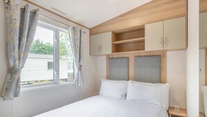 Een slaapkamer met een bed, gordijnen, een raam en houten kasten.