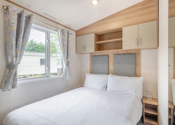 Une chambre à coucher avec un lit, des rideaux, une fenêtre et des meubles en bois.
