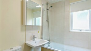Un bagno con lavandino, specchio, doccia e finestra.