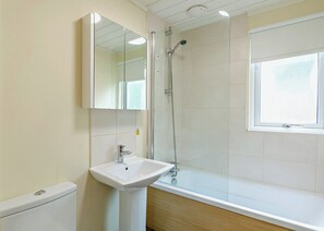 A bathroom with a sink, mirror, shower, and window. - Superior Lodge. With parking, ensuite and decking. (Great Yarmouth)