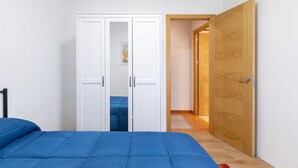 Un dormitorio con cama, armario y puerta de madera.