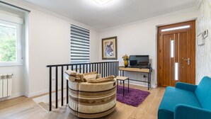 Una sala de estar con un sofá, un televisor, una puerta de madera y una ventana con persianas.