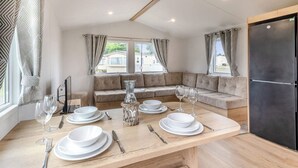 Een moderne keuken met een eettafel voor vier personen, een bank en een koelkast.