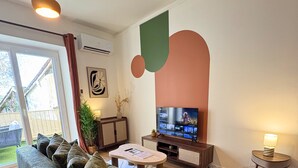 Un saló amb un sofà, una televisió, una taula petita i una làmpada.