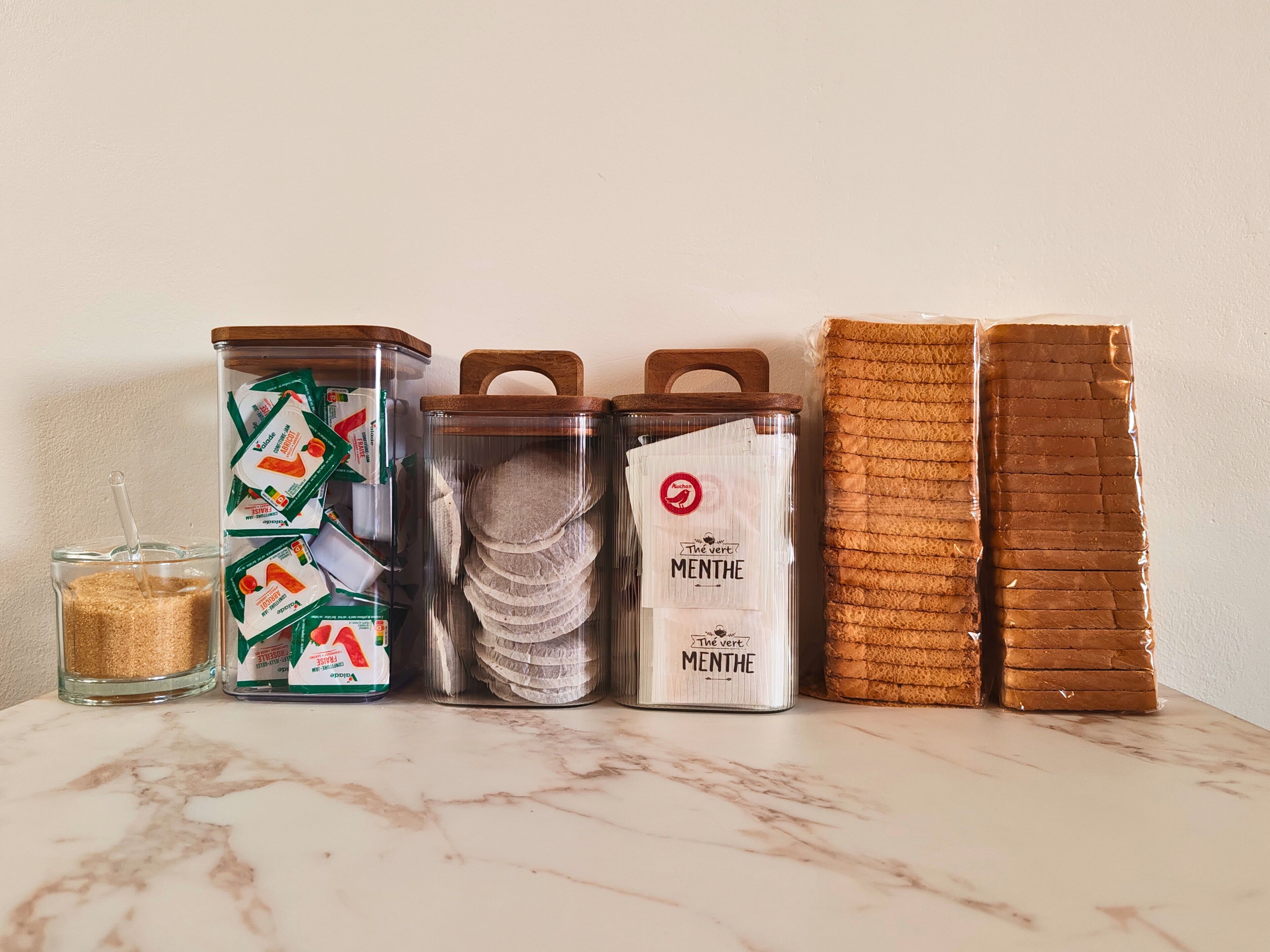 Een aanrecht met diverse etenswaren, waaronder verpakte producten, een glazen pot en brood.