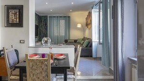 Uma sala de jantar com mesa posta para dois, um sofá ao fundo e vista para a sala de estar.