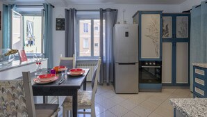 Uma cozinha moderna com geladeira, forno e área de refeições com mesa posta para dois.