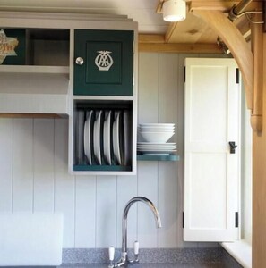 A kitchen with a built-in sink, a green cabinet with a logo, and a white door.