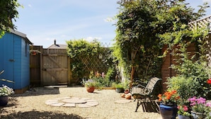 A garden with a wooden fence, a blue shed, and a bench. - Mead Cottage (Bridport)