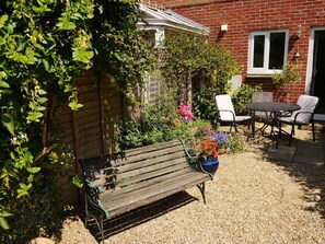Eine Holzbank, ein Tisch mit Stühlen und ein Blumentopf in einem Garten.