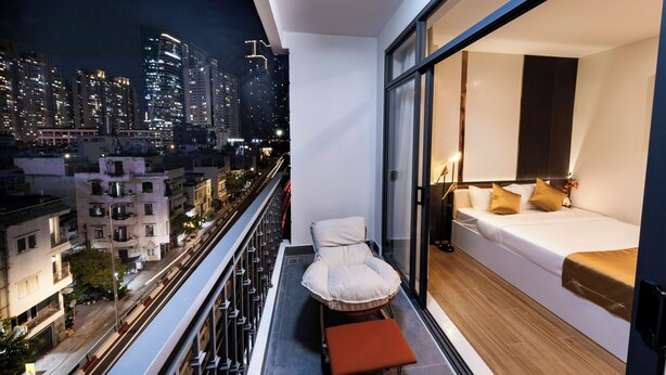 A balcony with a city view, a bed with pillows, and a chair. - HomeAi Apartment - Binh Thanh near LM81 (Ho Chi Minh City)