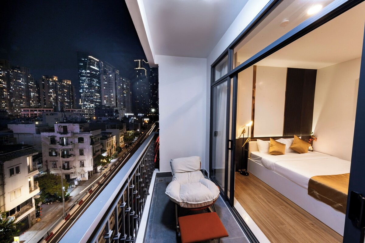 Ein Balkon mit Blick auf die Stadt, ein Bett mit Kissen und ein Sessel.