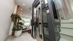 A modern elevator with glass doors, a potted plant, and a visible emergency phone. - HomeAi Apartment - Binh Thanh near LM81 (Ho Chi Minh City)