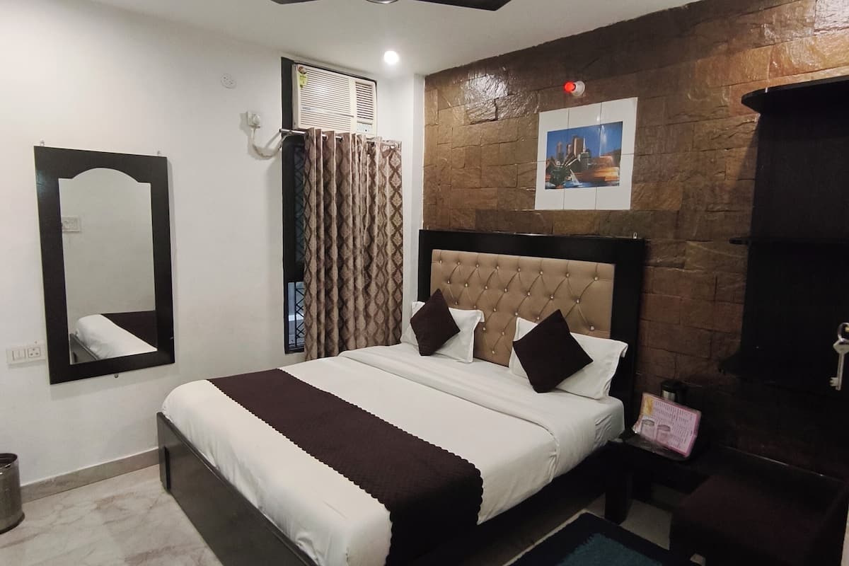 A bedroom with a bed, a ceiling fan, a nightstand, a mirror, a picture on the wall, and a window with curtains.