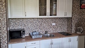 A kitchen with white cabinets, a microwave, a sink, and a coffee maker. - Welcoming 1-bedroom villa with AC in Radovići (Radovići)