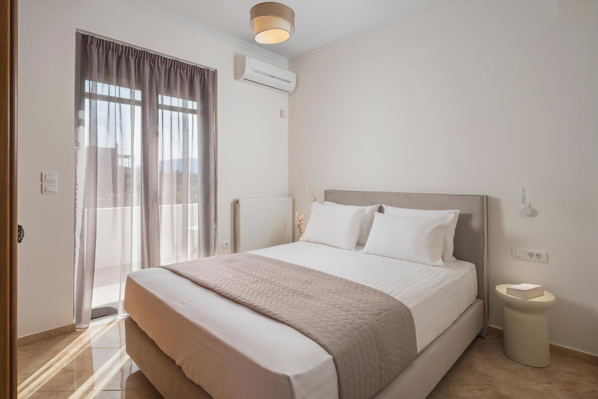 A bedroom with a bed, a bedside table, a window with curtains, an air conditioning unit, and a wall-mounted light fixture.