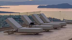 A rooftop terrace with lounge chairs and a city view. - Lithea Estate Collection (Chania)