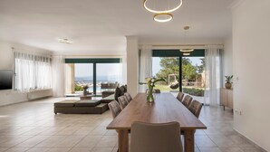 A spacious living area with a large dining table, comfortable seating, and a view of the outdoors. - Lithea Estate Collection (Chania)
