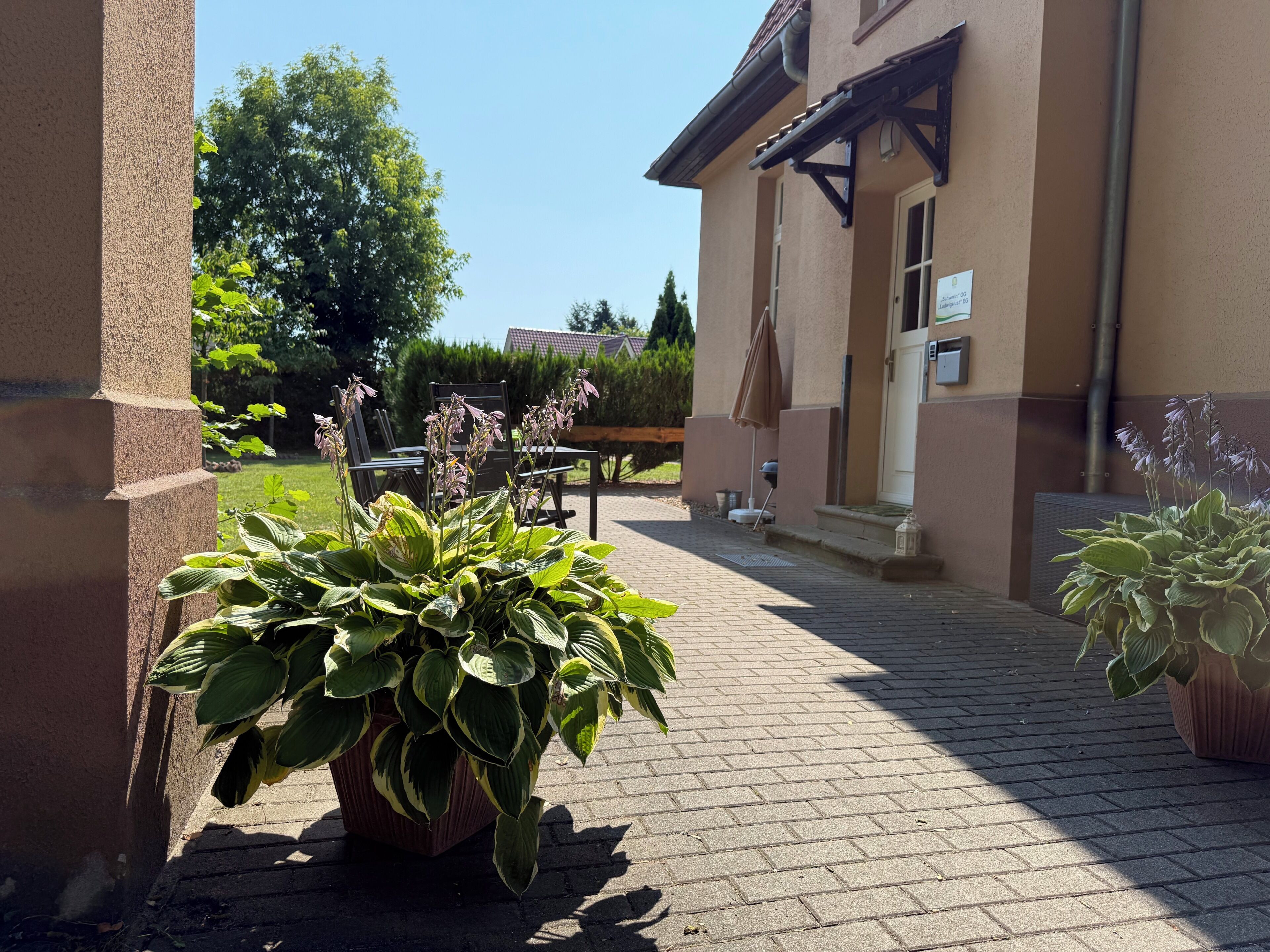 Ein gepflasterter Innenhof mit Blumentöpfen, Gartenmöbeln und einem Hauseingang.