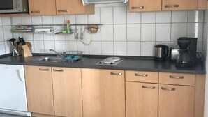 Una cocina con armarios de madera, microondas, fregadero y cafetera.