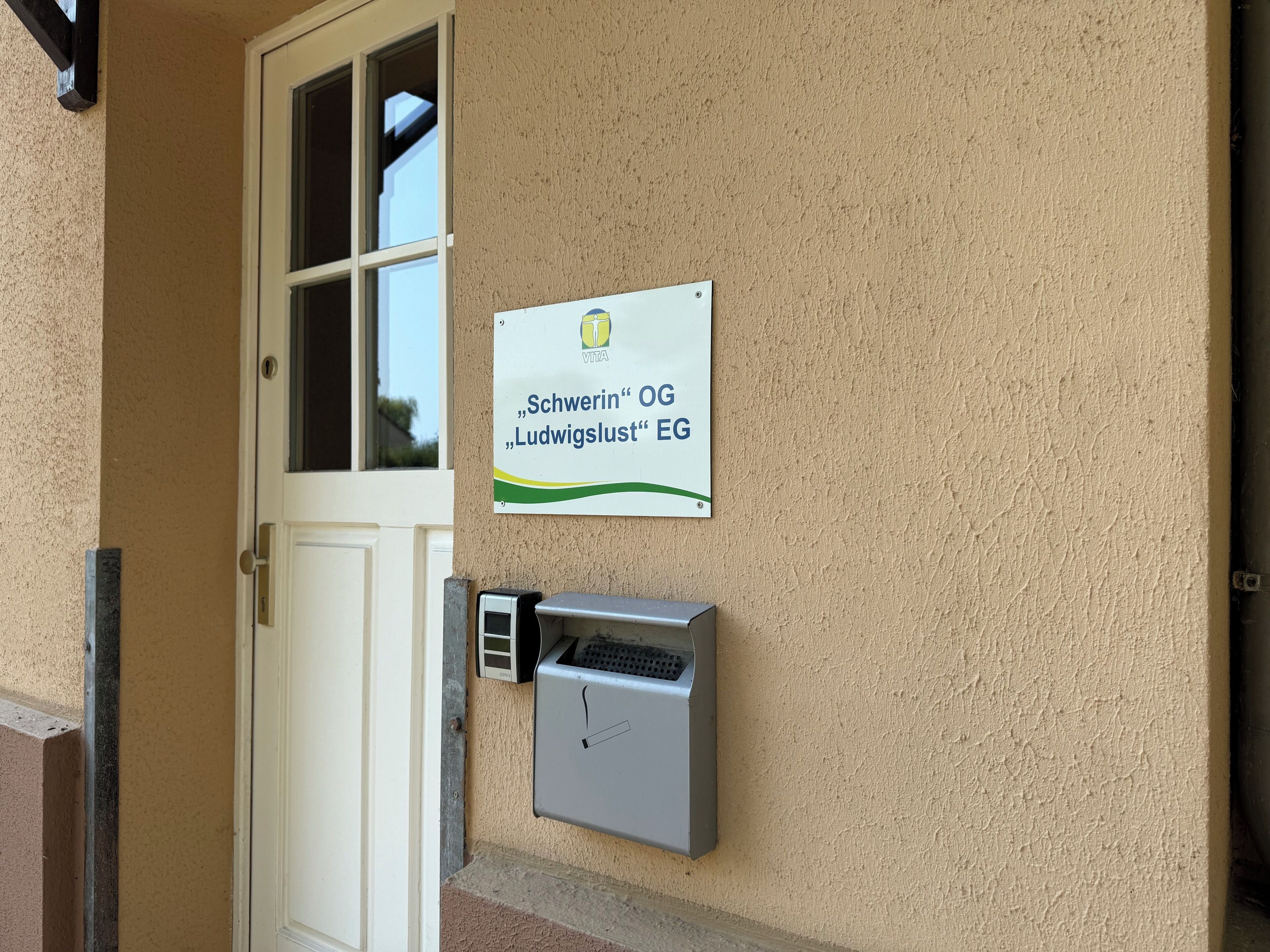 En dør med et skilt over, et vindue og en fastmonteret eltavle.