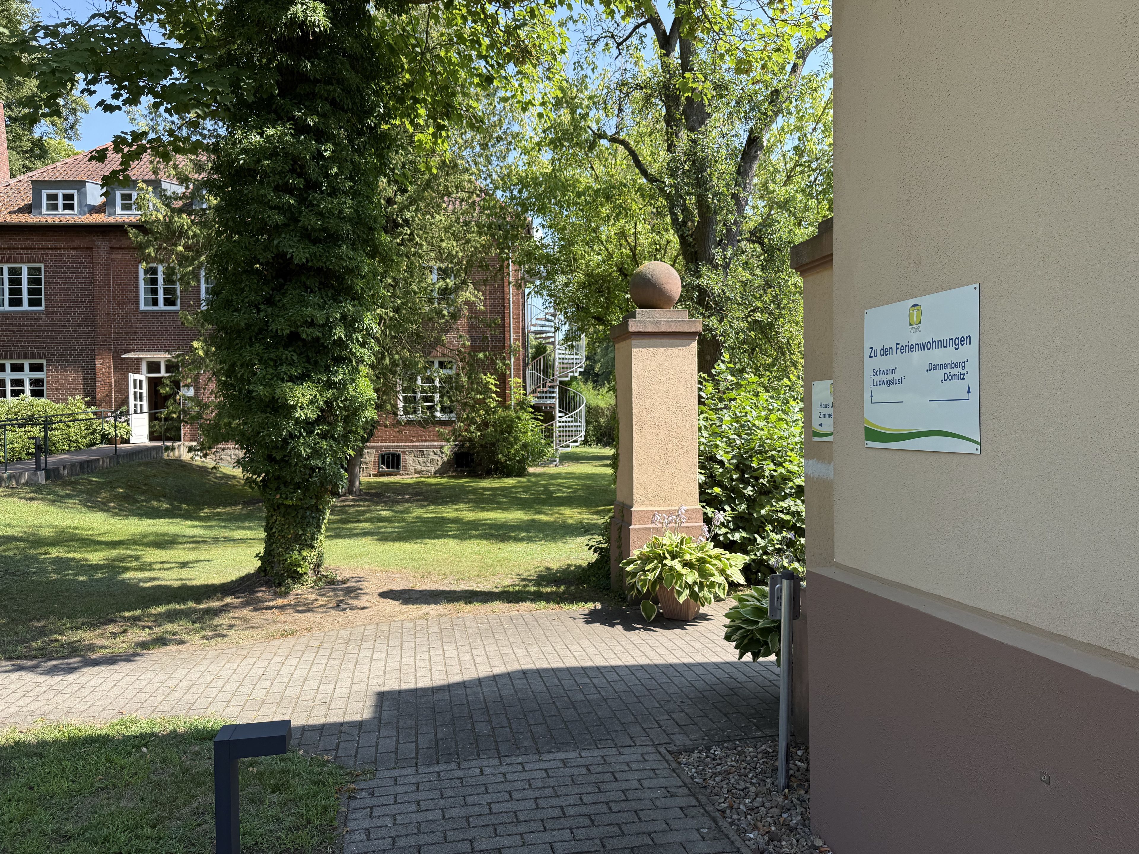 A courtyard with a brick building, a stone staircase, and a sign indicating directions to different parts of the property.