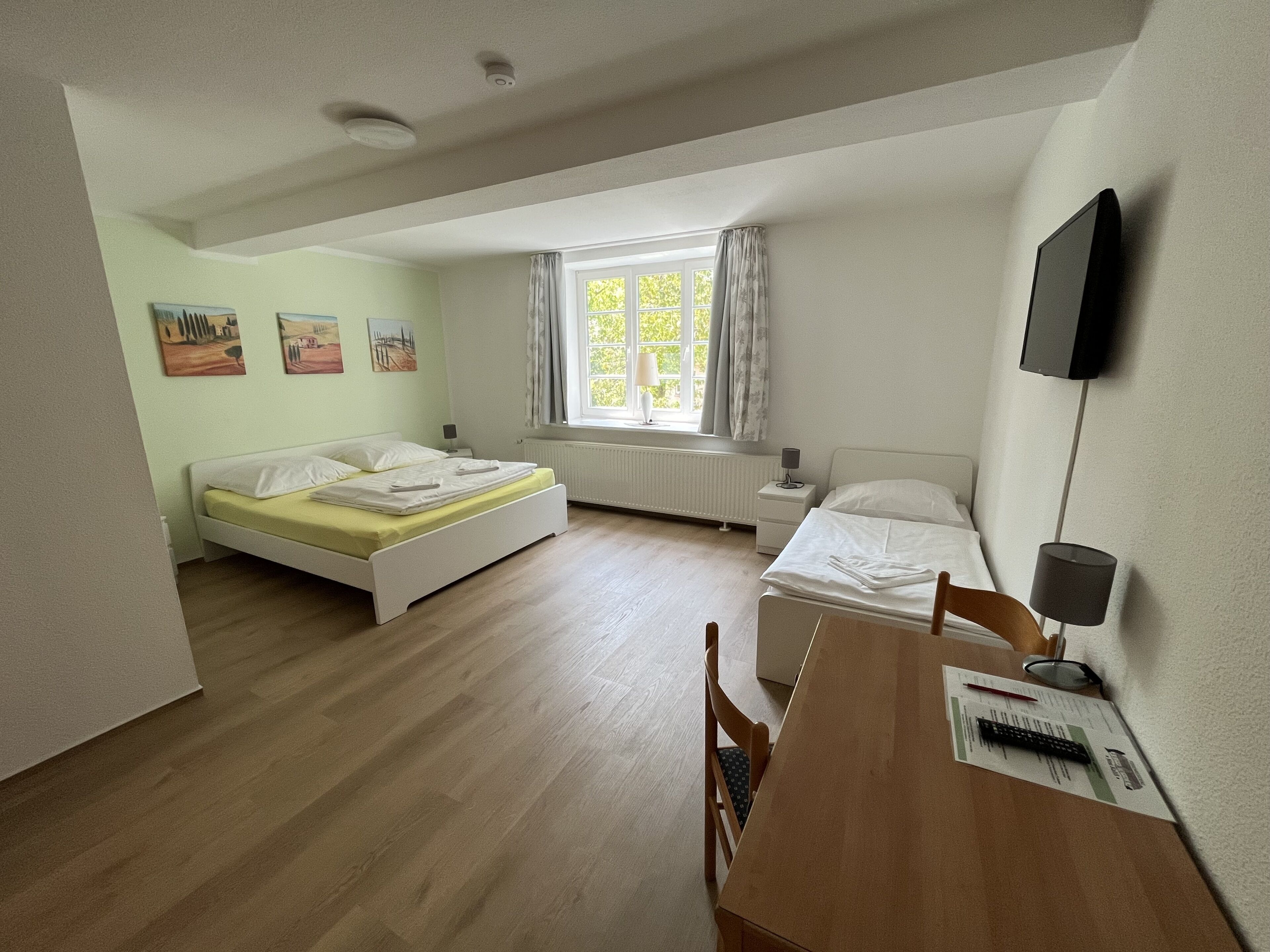 Ein Schlafzimmer mit zwei Betten, einem Schreibtisch und einem Fernseher.