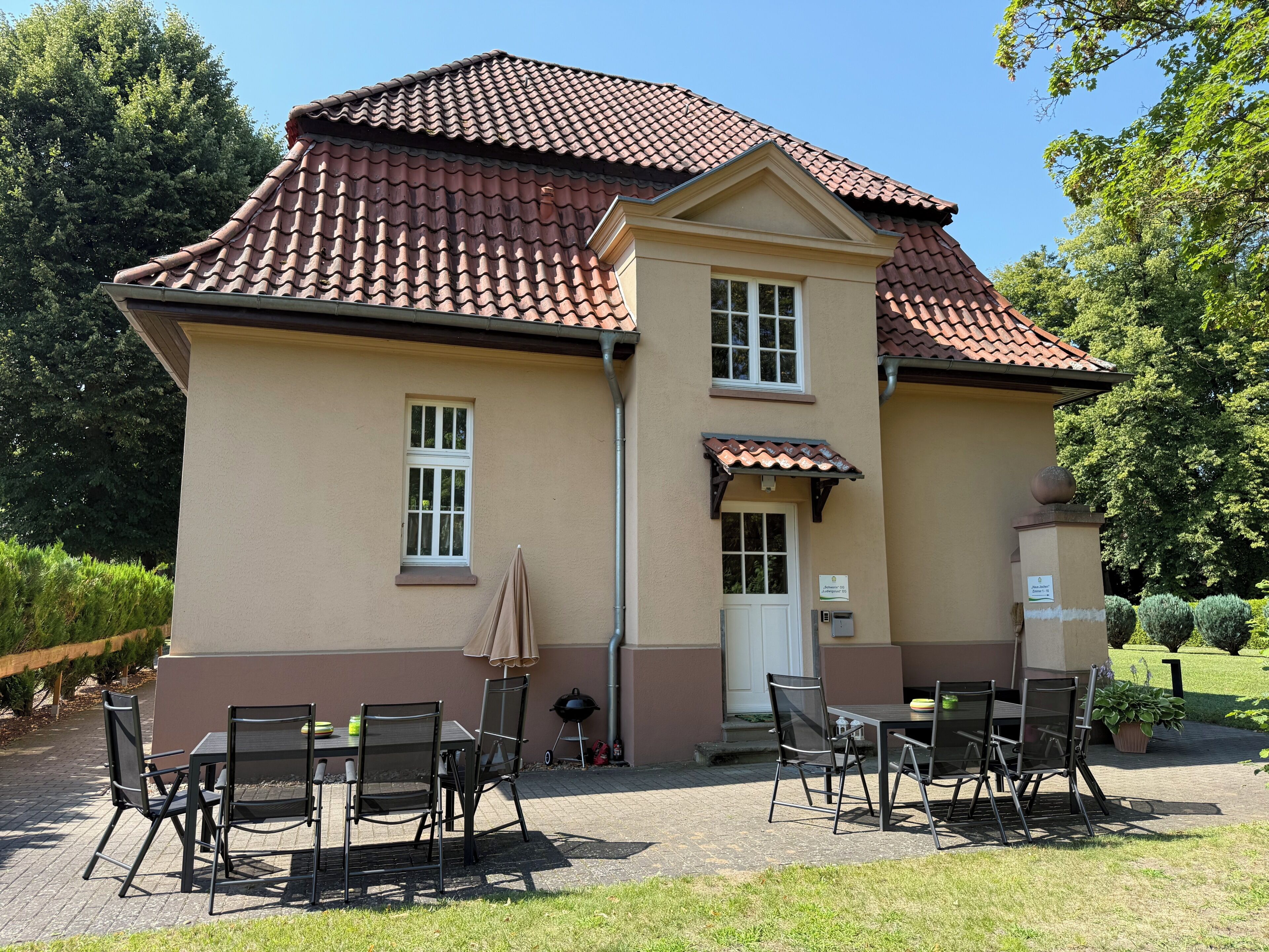 A two-story building with a tiled roof, a front door, and a small window.