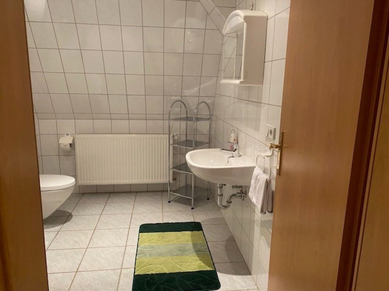 Une salle de bain comprenant des toilettes, un radiateur, un lavabo et un espace douche.