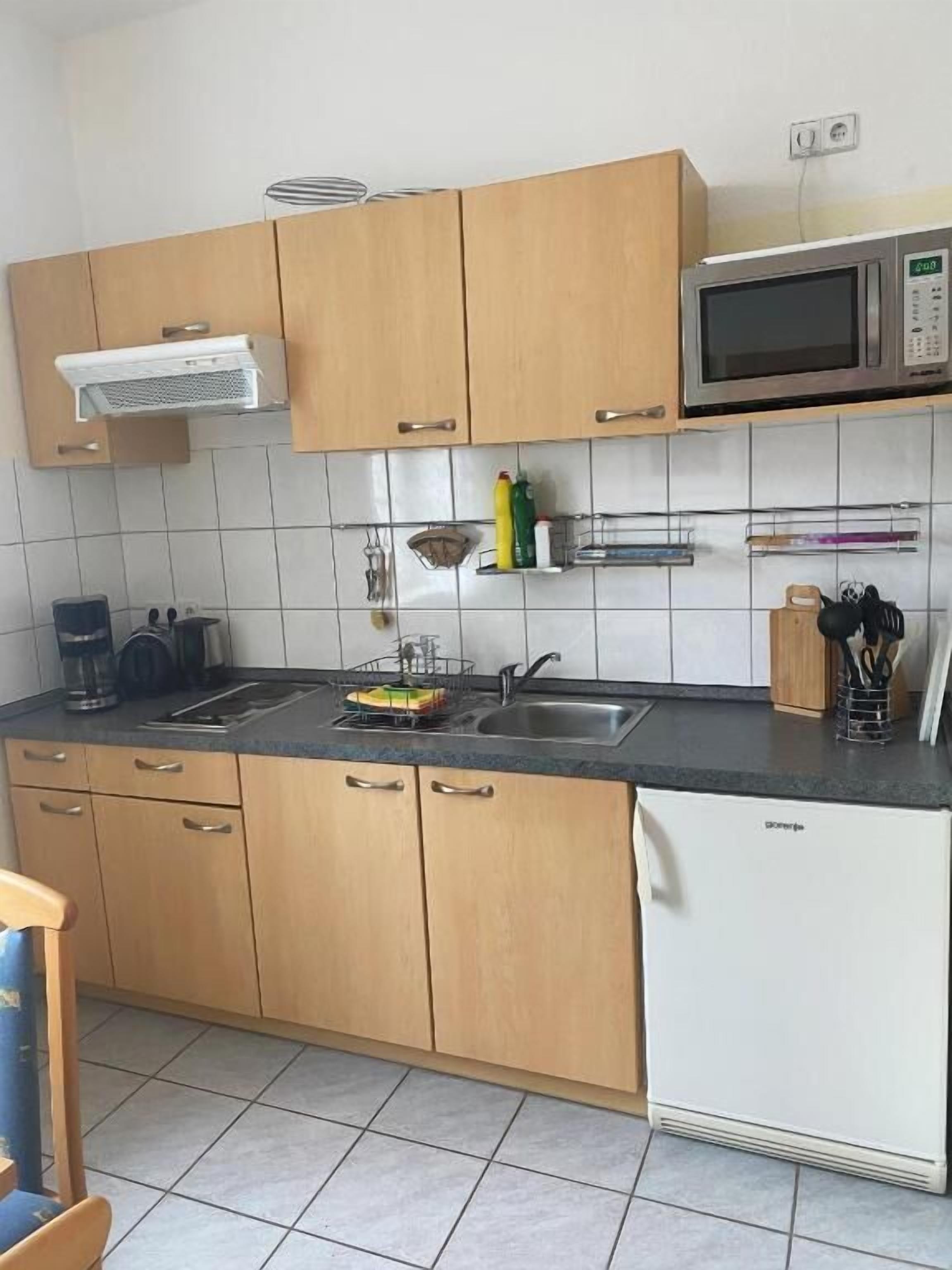 Eine Küche mit Holzausstattung, einer Mikrowelle, einem Geschirrspüler und einem Spülbecken.