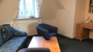 Un salón estilo loft con un sofá, un sillón y una mesita.