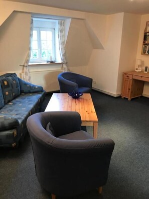 En stue i loftstil med sofa, lænestol og et lille bord.