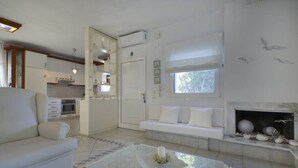 Una sala de estar moderna con un sofá, una mesa de centro de vidrio, una chimenea y una cocina al fondo.