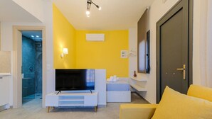 Een woonkamer met een televisie, een bank, een bed en een deur.