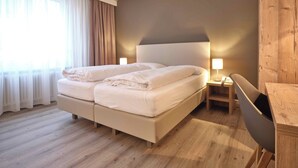 Habitación de hotel con una cama grande, lámparas de noche, un escritorio de madera y vistas al exterior.