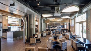 Un restaurante espacioso con techos altos, conductos expuestos y diversas opciones de asientos, incluyendo cabinas y mesas.