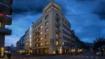 Un hôtel à plusieurs étages doté de balcons, d’un restaurant et d’une entrée bien visible.