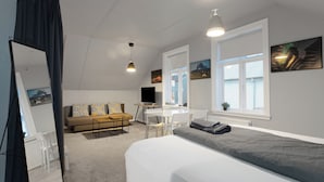 Un dormitorio moderno con una cama grande, un escritorio, un sofá y una ventana con una obra de arte.