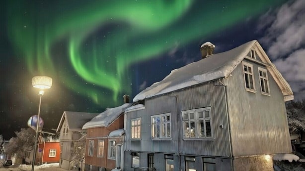 Una hilera de casas con nieve en el suelo y un farol.