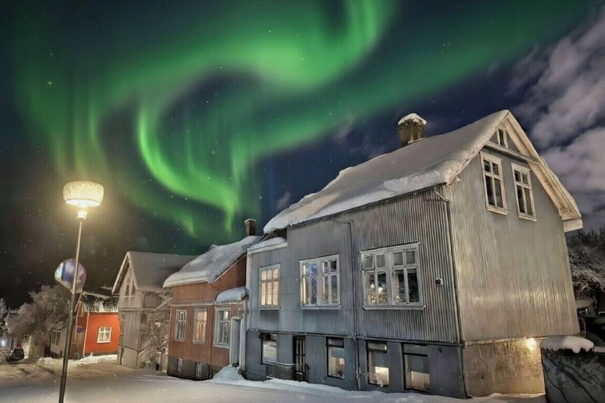 A row of houses with snow on the ground and a street lamp.