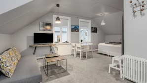 Un loft moderno y bien iluminado con techo alto, un televisor de pantalla plana, zona de comedor y un rincón de descanso acogedor.