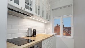 Una cocina moderna con armarios blancos, encimera de madera, cocina integrada y ventana con vista a una zona residencial.