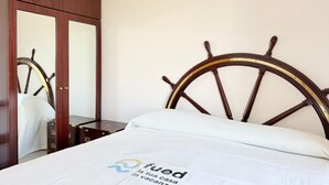 A bedroom with a bed, a wooden wardrobe, and a headboard with a ship's wheel design. - M462 - Marcelli, three-room apartment near the sea (Marcelli)