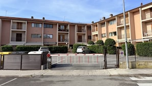 A multi-story residential building with balconies, a gated entrance, and a parked car. - M462 - Marcelli, three-room apartment near the sea (Marcelli)