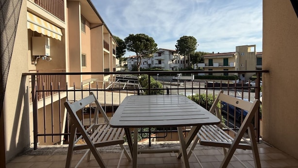 A balcony with a table and chairs, a view of neighboring buildings, and a clear sky. - M462 - Marcelli, three-room apartment near the sea (Marcelli)