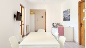 A modern room with a dining table, chairs, a TV, a refrigerator, and a painting on the wall. - M462 - Marcelli, three-room apartment near the sea (Marcelli)