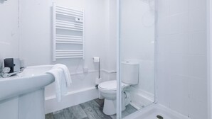 Un baño con bañera, inodoro y cabina de ducha de vidrio.