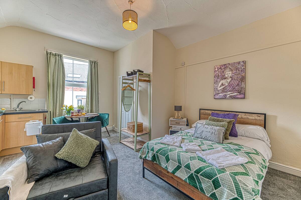 A bedroom with a bed, a bedside table, a chair, a wardrobe, a window, and a painting on the wall.
